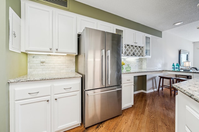 2950 Dean Pkwy Unit 2005, Minneapolis, MN 55416 - kitchen featuring freestanding refrigerator, white cabinets, glass insert cabinets, wood finished floors, and decorative backsplash