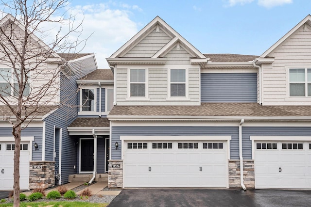 view of front facade with a garage, aphalt driveway, stone siding, and a shingled roof