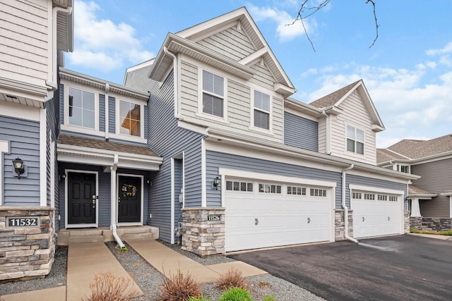 view of front of property with an attached garage, aphalt driveway, and stone siding