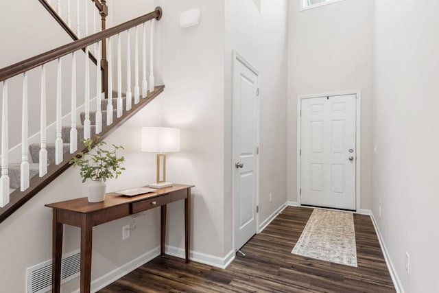 foyer featuring stairway, baseboards, visible vents, and dark wood-type flooring