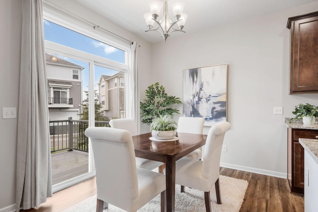 dining room featuring light wood-style floors, baseboards, and a notable chandelier