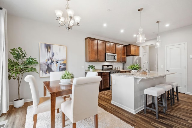 kitchen with a kitchen island with sink, a kitchen bar, dark wood-type flooring, recessed lighting, and appliances with stainless steel finishes