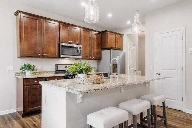 kitchen featuring appliances with stainless steel finishes, baseboards, a kitchen island with sink, and dark wood finished floors