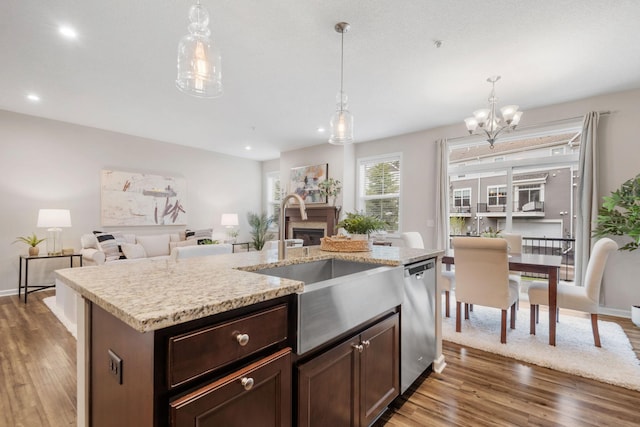 kitchen featuring wood finished floors, a sink, dishwasher, and a fireplace