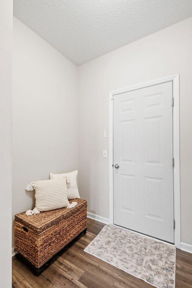 interior space with a textured ceiling, baseboards, and wood finished floors
