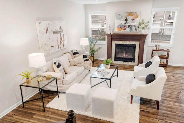 living area with baseboards, a glass covered fireplace, and wood finished floors