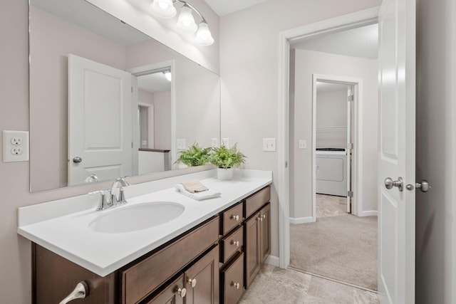 bathroom with baseboards, washer / dryer, and vanity