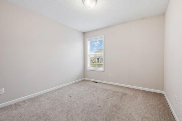 unfurnished room with carpet floors, a textured ceiling, baseboards, and visible vents