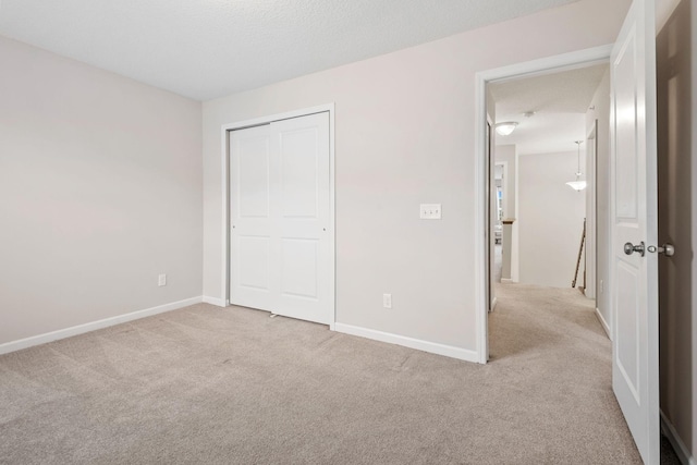 unfurnished bedroom with carpet floors, baseboards, and a closet
