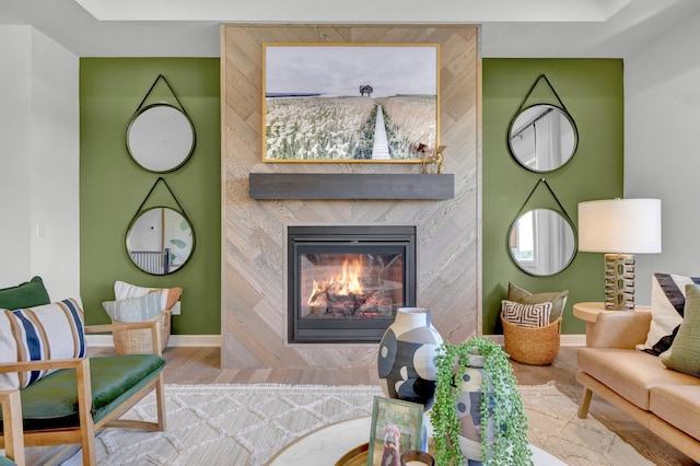 living area with a large fireplace, wood finished floors, and baseboards