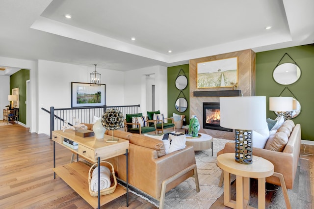 living room featuring recessed lighting, a raised ceiling, wood finished floors, and baseboards