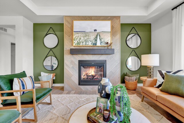 living area featuring baseboards, wood finished floors, and a raised ceiling