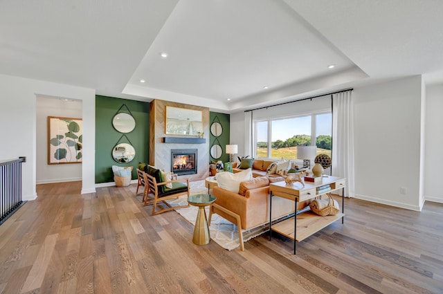 living room with a tray ceiling, baseboards, and recessed lighting