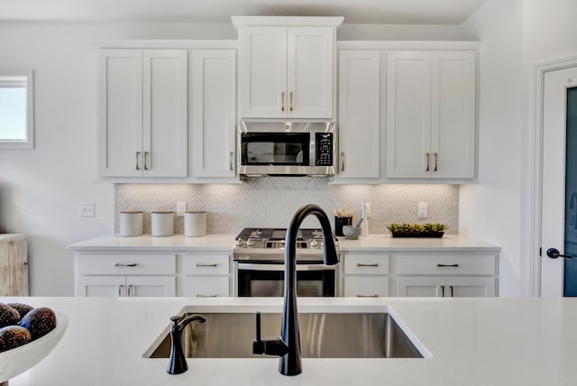 kitchen featuring white cabinets, stainless steel appliances, light countertops, and backsplash