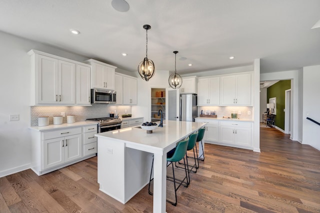 kitchen featuring white cabinets, stainless steel appliances, wood finished floors, and decorative backsplash