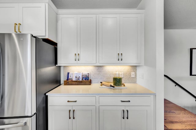 kitchen with white cabinets, light countertops, and freestanding refrigerator