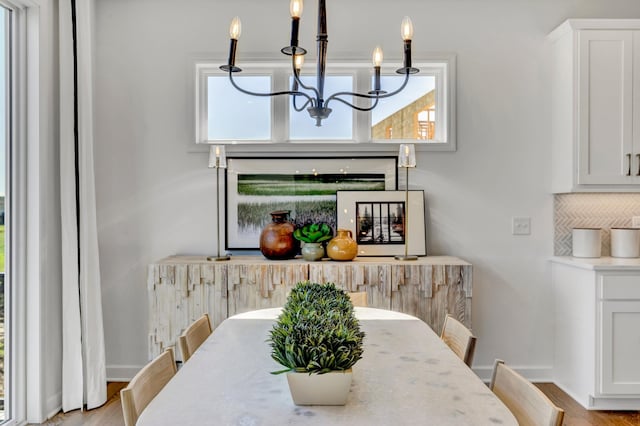 dining area featuring light wood-style flooring, a healthy amount of sunlight, and an inviting chandelier