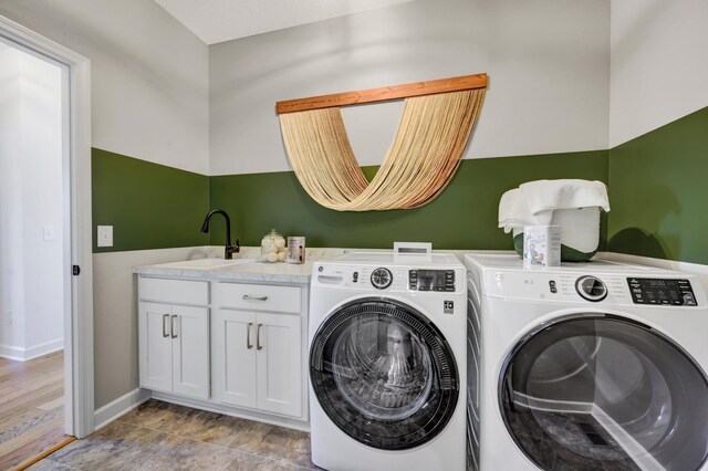 clothes washing area with separate washer and dryer, baseboards, a sink, and cabinet space