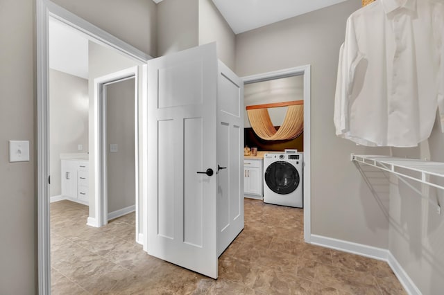 clothes washing area featuring baseboards, washer / clothes dryer, and cabinet space