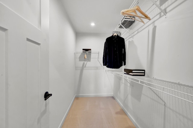walk in closet with light carpet
