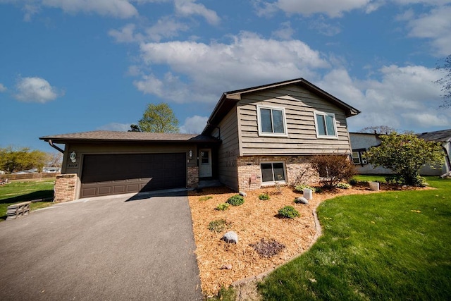 split level home featuring a front lawn, driveway, brick siding, and an attached garage