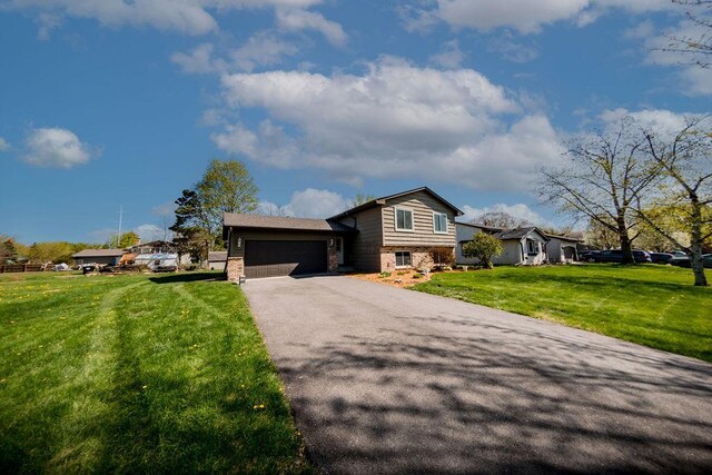 tri-level home with a front lawn, stone siding, aphalt driveway, and an attached garage