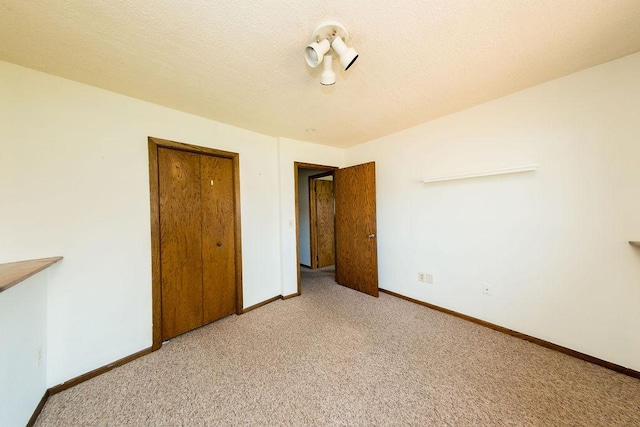 unfurnished bedroom featuring light carpet, baseboards, and a closet