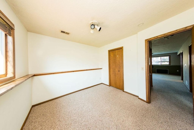 carpeted spare room featuring baseboards and visible vents