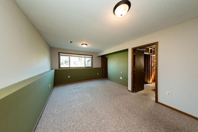 empty room with baseboards, a textured ceiling, visible vents, and carpet floors