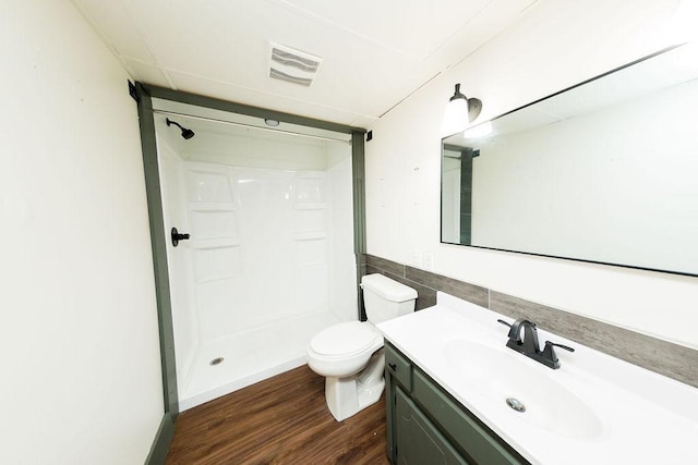 bathroom featuring toilet, wood finished floors, vanity, visible vents, and a shower stall
