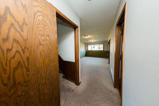 corridor with a textured ceiling and carpet floors