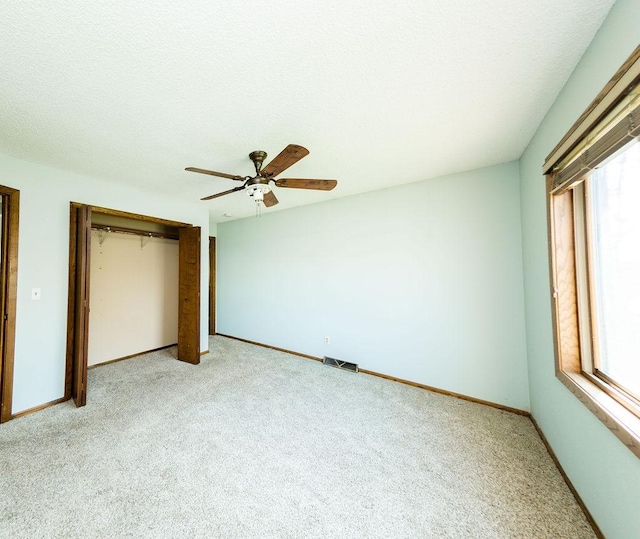 unfurnished bedroom featuring multiple windows, a closet, visible vents, and light colored carpet