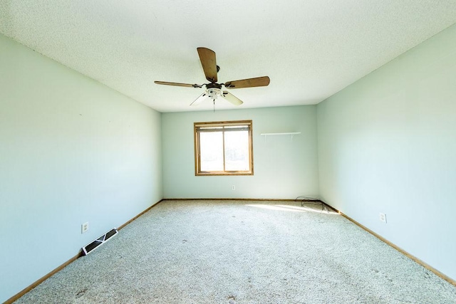 carpeted spare room featuring baseboards, ceiling fan, visible vents, and a textured ceiling