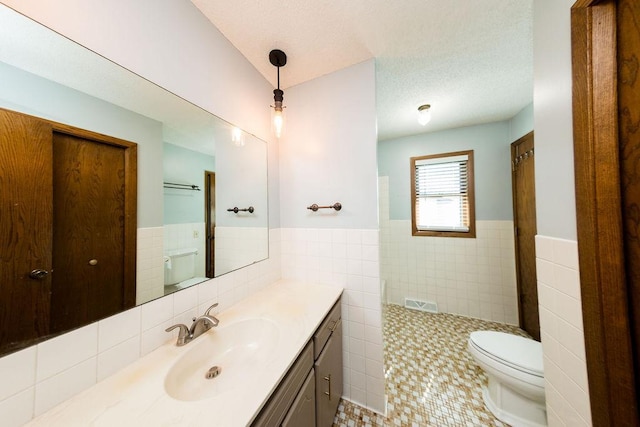 full bath featuring toilet, tiled shower, tile walls, tile patterned flooring, and wainscoting