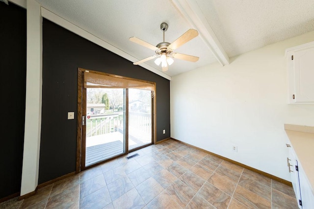 unfurnished dining area featuring lofted ceiling with beams, a textured ceiling, visible vents, a ceiling fan, and baseboards