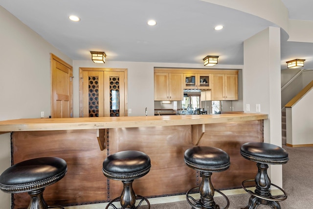 2625 Woodbridge Rd, Minnetonka Beach, MN 55391 - kitchen with glass insert cabinets, a breakfast bar, recessed lighting, carpet, and butcher block counters