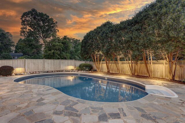 2625 Woodbridge Rd, Minnetonka Beach, MN 55391 - pool at dusk featuring a fenced backyard, a patio area, and view of wooded area