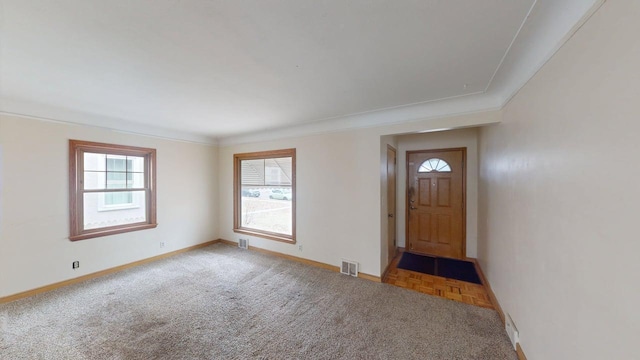 foyer entrance with carpet, visible vents, crown molding, and baseboards