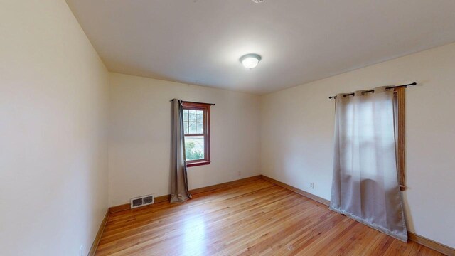unfurnished room featuring baseboards, visible vents, and light wood-style flooring