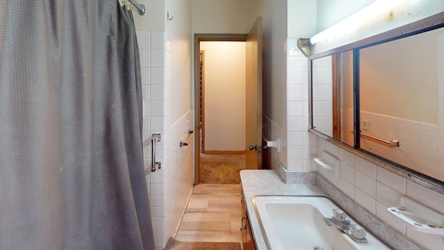 bathroom with tasteful backsplash, tile walls, a sink, and a shower with curtain