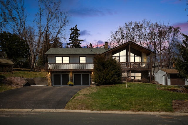 view of front of home with a storage shed, a chimney, a front lawn, and aphalt driveway