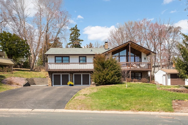 view of front of home featuring a garage, a chimney, a front yard, and aphalt driveway