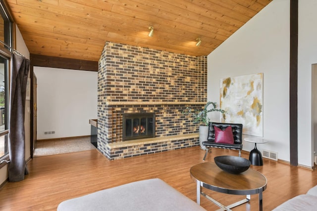 living area with wood ceiling, visible vents, a fireplace, wood finished floors, and lofted ceiling
