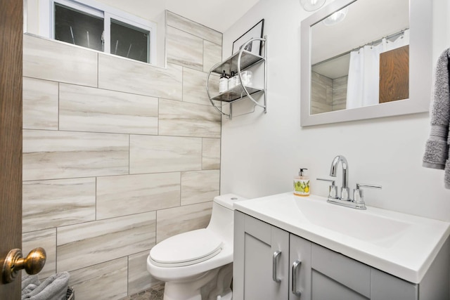 bathroom with vanity, a tile shower, and toilet