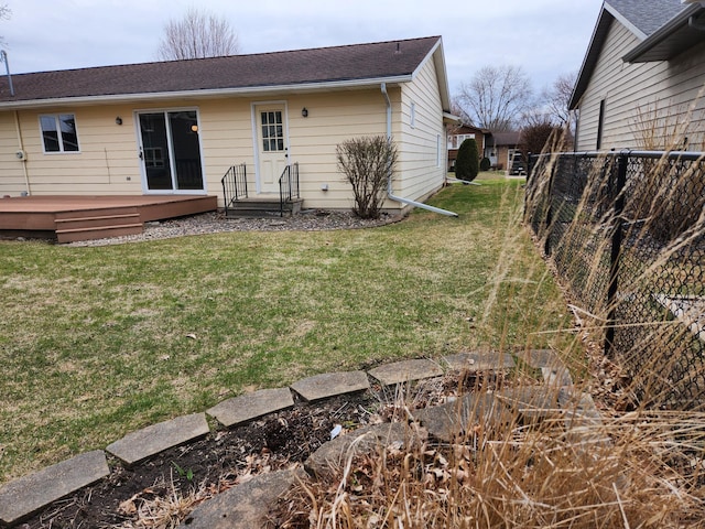 rear view of house featuring a yard, a wooden deck, and fence