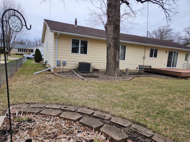 rear view of property with fence, a wooden deck, a lawn, and central air condition unit