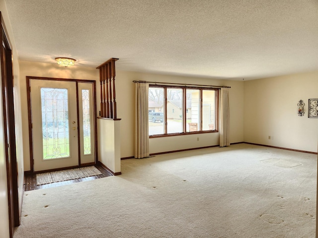 foyer entrance with carpet flooring, baseboards, and a textured ceiling