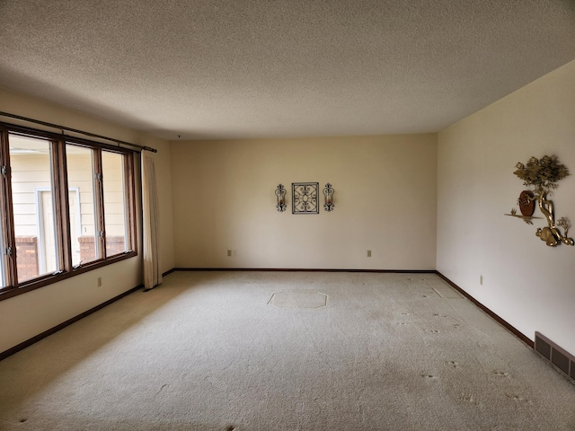 empty room featuring visible vents, baseboards, light carpet, and a textured ceiling