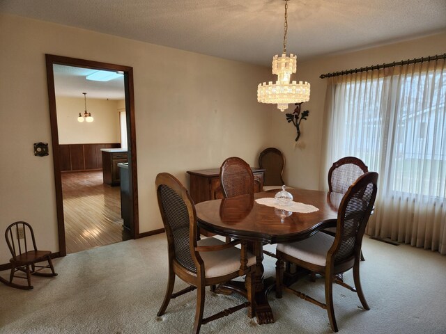 dining space featuring an inviting chandelier, light carpet, and a textured ceiling