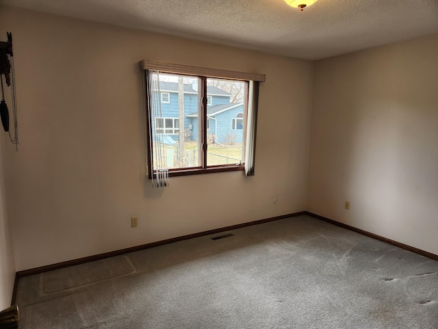 empty room featuring visible vents, baseboards, carpet flooring, and a textured ceiling